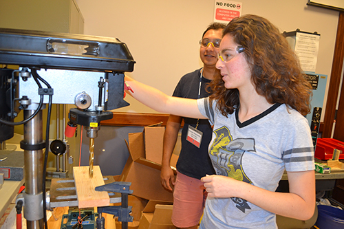 Sarah Schoenbaum (right) uses a drill press to work on a piece of her team's 3D printer, supervised by MechSE grad student Sameer Muckatira. 